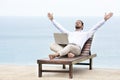 Young businessman on the beach resting on his deck chair using his tablet Royalty Free Stock Photo