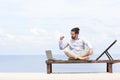 Young businessman on the beach resting on his deck chair using his tablet Royalty Free Stock Photo