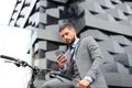 Young businessman with bicycle and smartphone on city street.