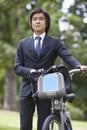 Young businessman with bicycle standing at park