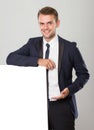 Young businessman in black suit leaning on blank white sign Royalty Free Stock Photo