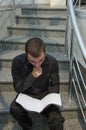 Young businessman in black suit sitting on stairs and reading the documentation papers Royalty Free Stock Photo