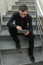 Young businessman in black suit sitting on stairs and reading the documentation papers. Royalty Free Stock Photo