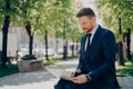 Young businessman working on laptop while sitting on bench in city park Royalty Free Stock Photo