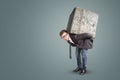 Businessman carrying a large and heavy stone on his back