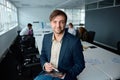 Young businessman in businesswear sitting on desk with digital tablet and digitized pen in office