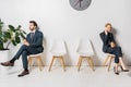 young businessman and businesswoman holding paper cups and waiting on chairs Royalty Free Stock Photo