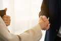 Young businessman and businesswoman shake hand together, hold tablet, standing, wear suit, sunlight at window background. Young Royalty Free Stock Photo