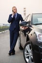 Young businessman in dark blue suit calling on cell phone next to his car Royalty Free Stock Photo