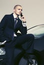 Young businessman calling on cell phone sitting on his car Royalty Free Stock Photo