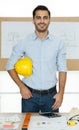 Young businessman in a casual business shirt and jeans holding yellow engineer hard hat standing with self-confidence and looking Royalty Free Stock Photo