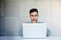 Young Businessman in Casual Shirt Working on Computer Laptop in Office. Hand on Shin, Sitting on Desk. Concentrated in Computer Royalty Free Stock Photo