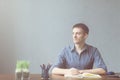 Young businessman caucasians sitting at desk office table and taking notes in notebook. Writing and looking out the window