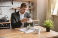 Young businessman checking news in his smartphone while reading magazine in the kitchen drinking morning coffee before going to Royalty Free Stock Photo