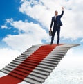 Young businessman climbing stairs and red carpet into sky Royalty Free Stock Photo