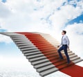 Young businessman climbing stairs and red carpet into sky Royalty Free Stock Photo