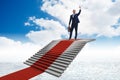 The young businessman climbing stairs and red carpet into sky Royalty Free Stock Photo