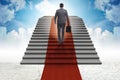 The young businessman climbing stairs and red carpet into sky Royalty Free Stock Photo