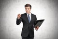 Young businessman with clipboard writing, concrete