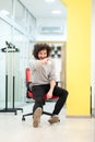 Young businessman with clumsy hair having fun at the office. Man on rolling chair throwing paper ball at colleagues Royalty Free Stock Photo