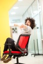 Young businessman with clumsy hair having fun at the office. Man on rolling chair throwing paper ball at colleagues Royalty Free Stock Photo