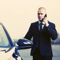 Young businessman in dark blue suit calling on cell phone next to his car Royalty Free Stock Photo