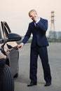 Young businessman in dark blue suit calling on cell phone next to his car Royalty Free Stock Photo