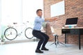 Young businessman doing exercises in office