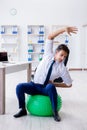 The young businessman doing sports stretching at workplace Royalty Free Stock Photo