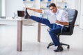 The young businessman doing sports stretching at workplace Royalty Free Stock Photo