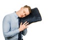 Young businessman dressed in blue shirt and tie sleeping with a pillow in his hands, isolated on white background Royalty Free Stock Photo
