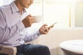 Young businessman drinking coffee and holding mobile phone while sitting by the window the office Royalty Free Stock Photo