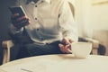 Young businessman drinking coffee and holding mobile phone while sitting by the window the office Royalty Free Stock Photo