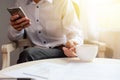 Young businessman drinking coffee and holding mobile phone while sitting by the window the office Royalty Free Stock Photo