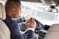 Young businessman driver sitting inside car drinking coffee joyful back seat view Royalty Free Stock Photo