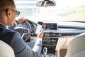 Young businessman driver in sunglasses sitting inside car driving using navigation app on smartphone back seat view Royalty Free Stock Photo