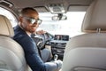 Young businessman driver in sunglasses sitting inside car looking back at camera joyful back seat view Royalty Free Stock Photo