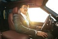 Young businessman in elegant suit driving luxury car