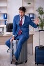 Young male employee preparing for trip at workplace Royalty Free Stock Photo