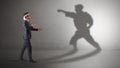 Young businessman fighting with his shadow