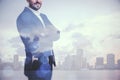 Young businessman with folded arms standing on blurry city background. Success, future and ceo concept. Double exposure Royalty Free Stock Photo