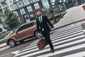 Young businessman.Full length of young man in full suit crossing the street while walking outdoors Royalty Free Stock Photo