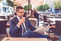 Young man with glass of water in hand reading newspaper at outdoor cafe Royalty Free Stock Photo