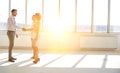 Young businessman greeting businesswoman with handshake standing by colleague in new office Royalty Free Stock Photo