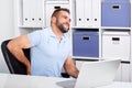 Young businessman has backache at work with a laptop Royalty Free Stock Photo