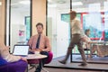 Young businessman having job interview whilst people work in an active office in the background, job hunting concept