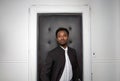 young businessman in his twenties wearing suit on black door background white wall man luxury lounge studio portrait