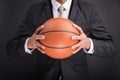 Young businessman holding basketball ball