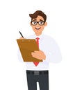 Young businessman holding clipboard and writing with pen. Trendy person checking file or checklist. Male character keeping folder. Royalty Free Stock Photo