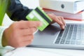 Young businessman holding a credit card and typing. On-line shopping on the internet using a laptop. Just hands over the